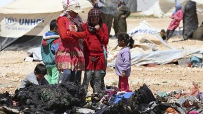 Syrian refugees children look at the remains of their belongings, which were damaged during a clash between security forces and Syrian refugees, at the Zaatari refugee camp in the Jordanian city of Mafraq, near the border with Syria, April 6, 2014