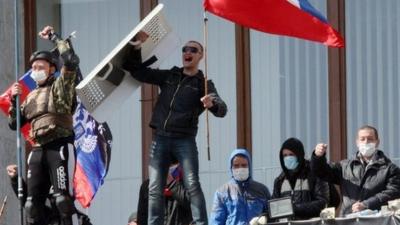 Pro-Russian activists who seized the main administration building in the eastern Ukrainian city of Donetsk hold Russian flag and flag of so-called Donetsk Republic