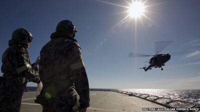 Crew aboard the Australian Navy ship HMAS Success watch as a helicopter participates in a Replenishment at Sea evolution with the Royal Malaysian Navy ship KD LEKIU in the southern Indian Ocean during the continuing search for the missing Malaysian Airlines flight MH370