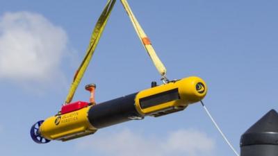 A submarine built by Bluefin Robotics is lowered down onto a boat at their headquarters in Quincy, Mass