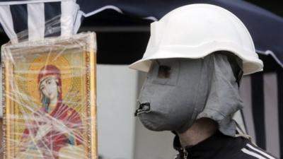 A Pro-Russian activist wears a hand-made mask behind a barricade in front of the regional administration building, in Donetsk, Ukraine