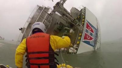 A rescue ship approaches a sinking ferry