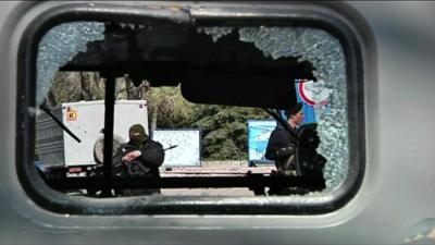 Armed men can be seen through a smashed window