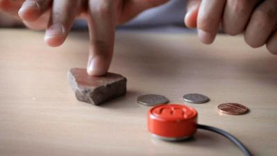 A person using a Mogees to turn a stone into a musical instrument