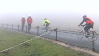 Rescuers walking along a road as cyclists ride past