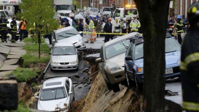 Cars sit on the edge of a sinkhole in the Charles Village neighborhood of Baltimore, Wednesday, April 30