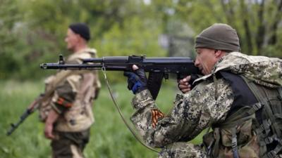 A pro-Russian rebel aims his rifle at a checkpoint near a Ukrainian airbase in Kramatorsk