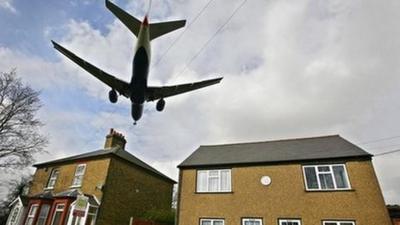 A passenger jet flies over rooftops as it prepares to land at Heathrow airport in west London