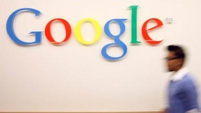 Man walks past Google sign