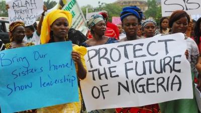 Women hold signs in support of the kidnapped Chibok girls