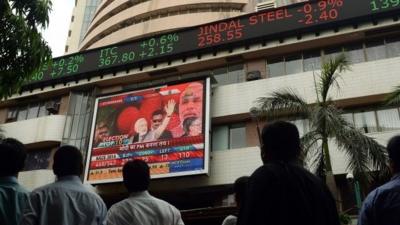 Indian pedestrians watch as a digital broadcast presents the rolling share price information