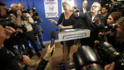 Journalists surround Marine Le Pen, France"s National Front political party head, who reacts to results after the polls closed in the European Parliament elections at the party"s headquarters in Nanterre, near Paris