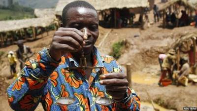 A trader weighs gold nuggets at an illegal mine-pit