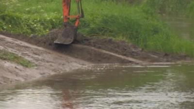 A bucket dredging silt from a river in Somerset