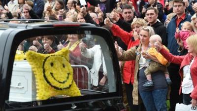 Bystanders give 'thumbs-up' sign to hearse carrying Stephen's coffin