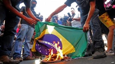 Protesters burning Brazilian flag