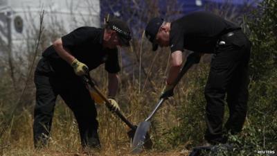 Two policemen searching scrubland