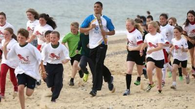 Anthony Ogogo runs with children on Lowestoft beach