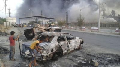 Iraqi children stand next to a vehicle destroyed during clashes between Sunni militants and Iraqi security forces in Mosul (10 June 2014)