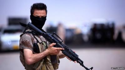 A masked Pershmerga fighter from Iraq's autonomous Kurdish region guards a temporary camp