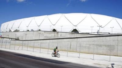 Andy Smith rides his bike past the Arena da Amazonia stadium