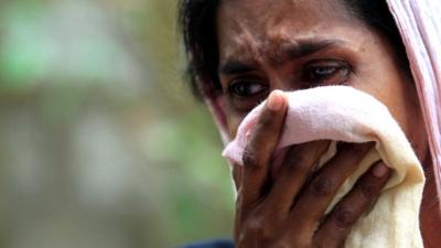 A Muslim woman cries next to her burnt house after a clash between Buddhists and Muslims in Aluthgama