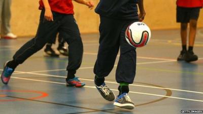 Children playing football in a school gym