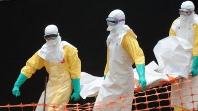 Medecins Sans Frontieres doctors carry the body of an Ebola victim