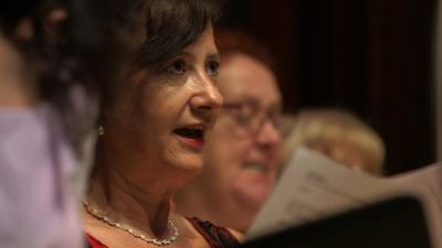 Woman singing in a choir with sheet music