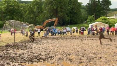 A player goes for a penalty kick in the mud