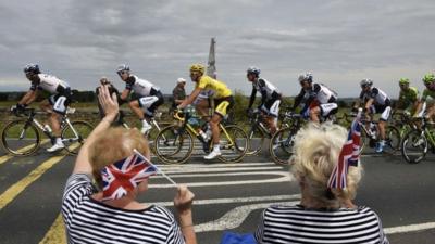 Supporters wave along the road as Germany's Marcel Kittel (C), wearing the overall leader's yellow jersey