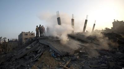 Palestinian inspect a house destroyed by an Israeli strike, 8 July 2014