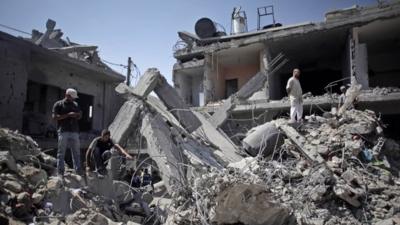 Palestinians search in the rubble of a destroyed house where eight members of the Al Haj family were killed in a strike early morning in Khan Younis refugee camp, southern Gaza Strip on Thursday, July 10, 2014