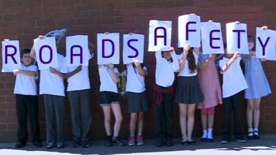 Children holding 'road safety' sign