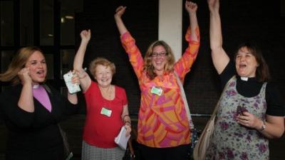 Female members of the clergy celebrate after members voted to approve the creation of female bishops at the Church of England General Synod in York,