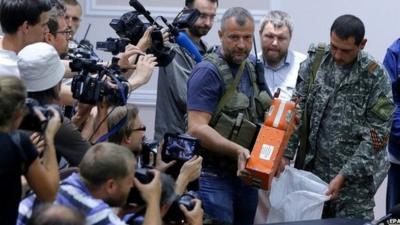 Rebel fighters unveil the flight-data recorders at a meeting with Malaysian officials in Donetsk