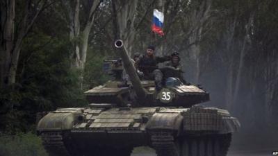 Pro-Russian rebels ride on a tank flying Russia's flag, on a road east of Donetsk, Monday