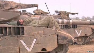 Israeli soldier sleeping on top of his tank