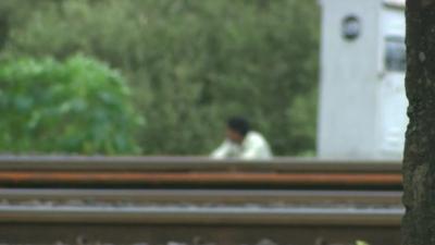 Man squatting next to a railway