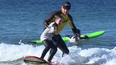 man teaching girl to surf