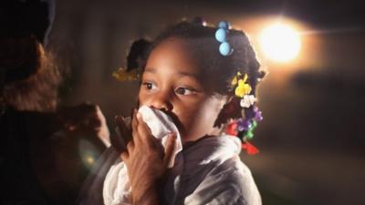 A child shields her mouth from tear gas fired by police on Monday night