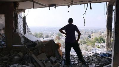 Palestinian man in rubble of apartment complex, Gaza