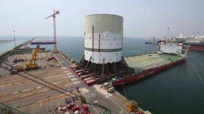 Still from time-lapse footage shows the largest piece of the turret being moved onto a barge