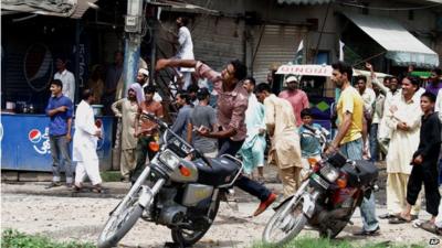 One of the supporters of Pakistan's ruling party throws a rock on a procession of cricketer-turned-politician Imran Khan in Gujranwala, Pakistan