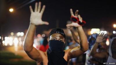 A demonstrator confronts police during a protest over the shooting of Michael Williams