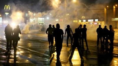 People are seen as police start to fire tear gas at a demonstrators protesting the shooting death of Michael Brown