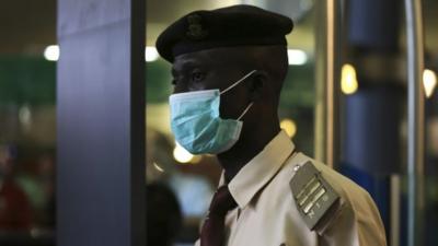 An immigration officer wears a face mask at an airport in Abuja