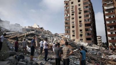 Palestinians look at the rubble of an 12-storey apartment building that collapsed after it was hit by missiles during an Israeli air strike