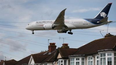 A passenger plane comes into land near housing at Heathrow Airport