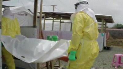 Two health workers carrying an Ebola victim